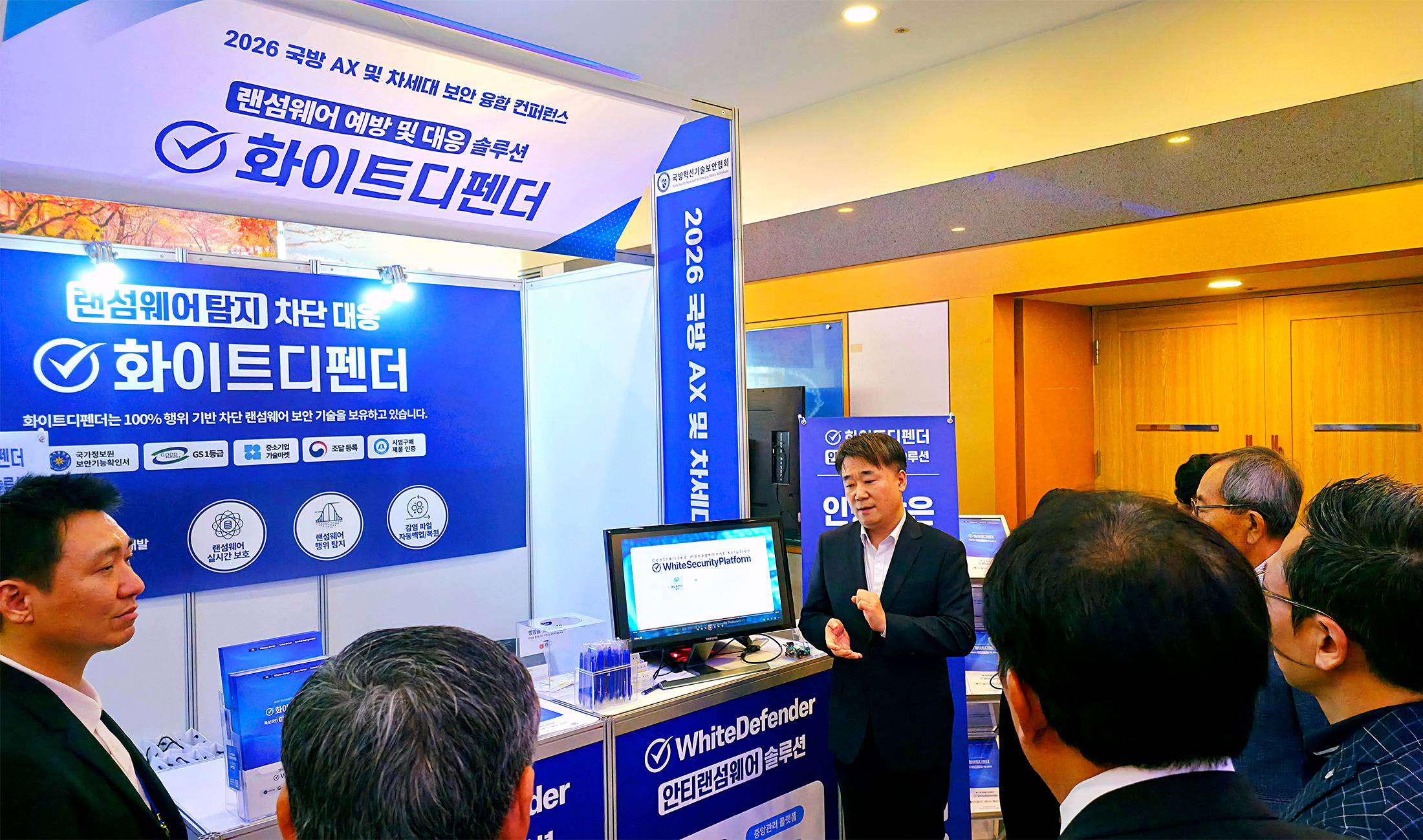 2026 국방 AX 및 차세대 보안 융합 컨퍼런스 에브리존 전시 부스에서 화이트디펜더를 소개하는 모습